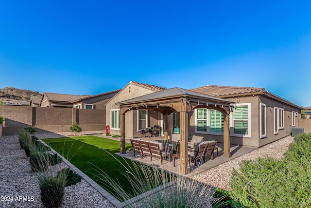 rear view of house with cooling unit, a gazebo, a lawn, and a patio area