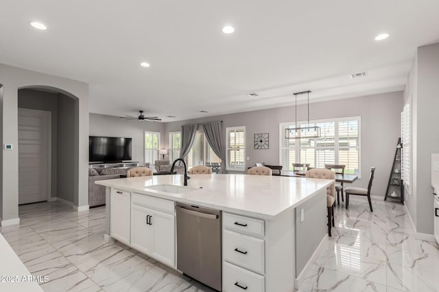 kitchen with pendant lighting, white cabinets, dishwasher, an island with sink, and sink