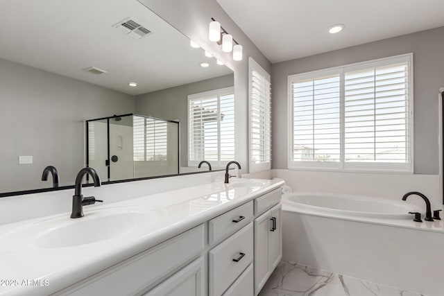 bathroom featuring independent shower and bath, a healthy amount of sunlight, and vanity