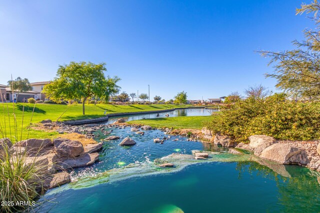 view of pool with a yard and a water view