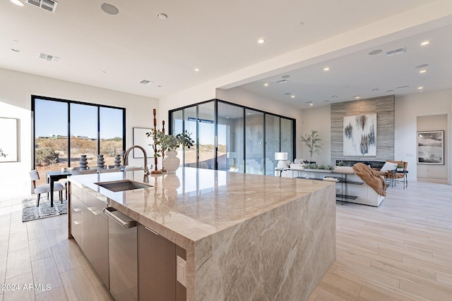 kitchen with a large fireplace, light stone counters, a large island, and sink