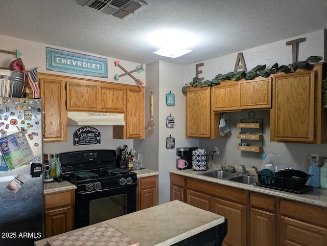 kitchen with black gas range oven, refrigerator, sink, and a textured ceiling