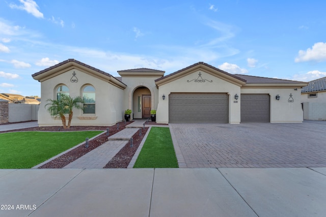 mediterranean / spanish house with a garage and a front lawn