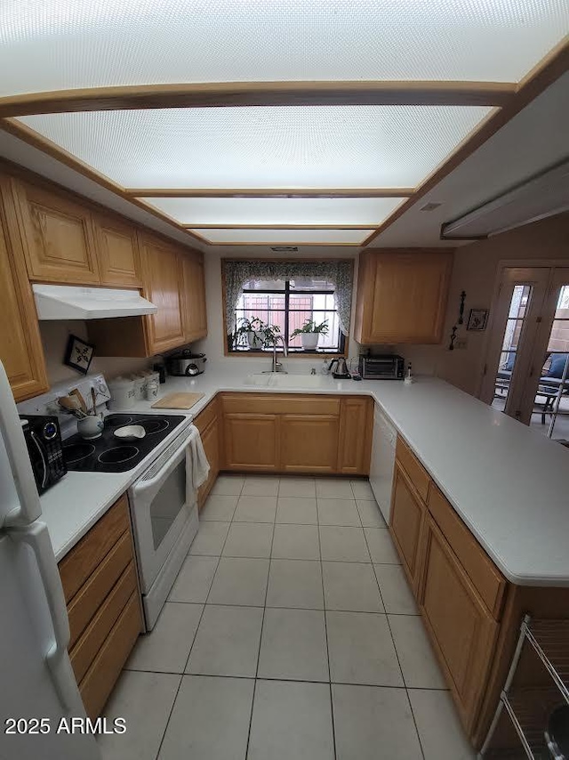 kitchen featuring white appliances, light countertops, under cabinet range hood, and a peninsula