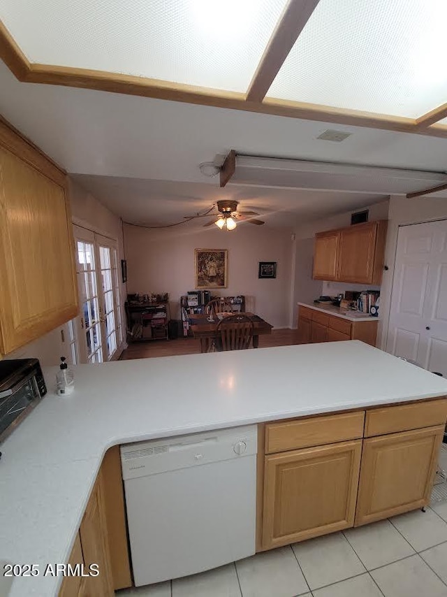 kitchen featuring light tile patterned floors, dishwasher, ceiling fan, a peninsula, and light countertops