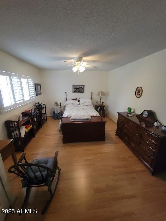 bedroom with light wood-style floors, ceiling fan, and a textured ceiling