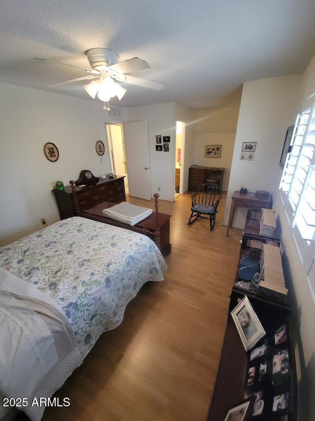 bedroom with ceiling fan, a textured ceiling, and light wood-style flooring