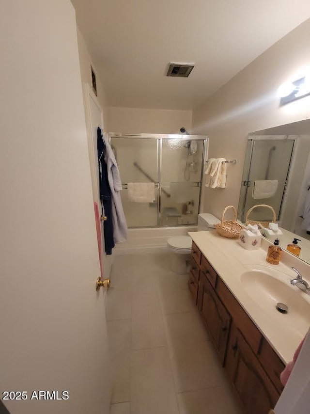 bathroom featuring visible vents, toilet, enclosed tub / shower combo, vanity, and tile patterned flooring