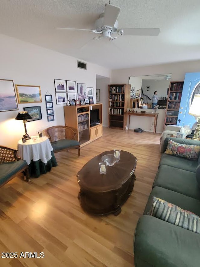 living room with visible vents, ceiling fan, a textured ceiling, and wood finished floors