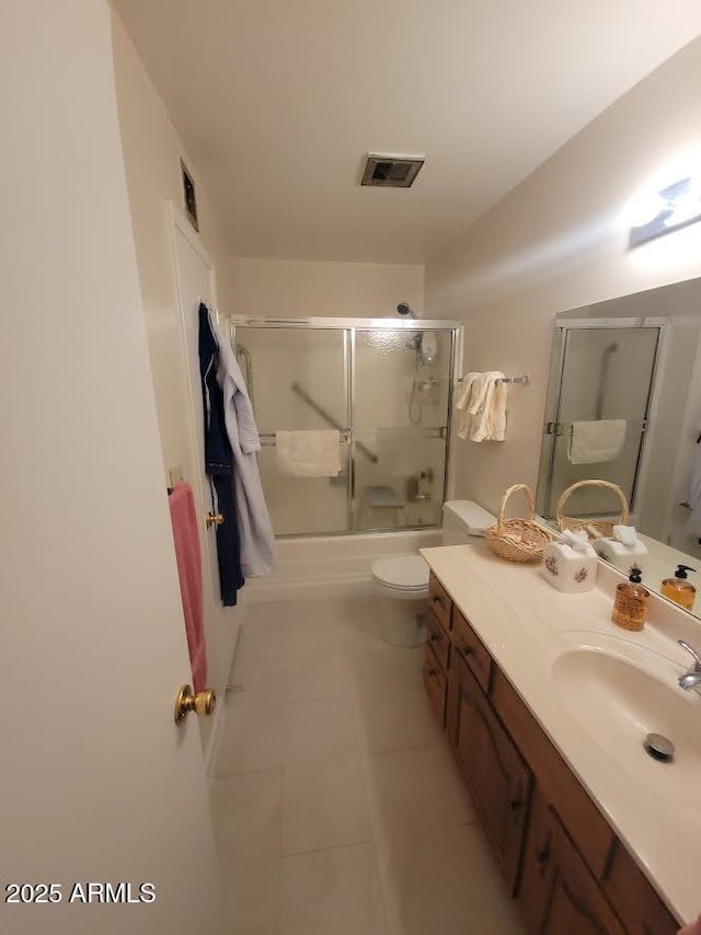 bathroom with tile patterned flooring, toilet, vanity, visible vents, and combined bath / shower with glass door