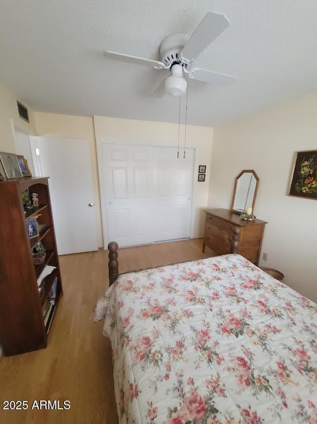 bedroom featuring a ceiling fan, visible vents, and wood finished floors