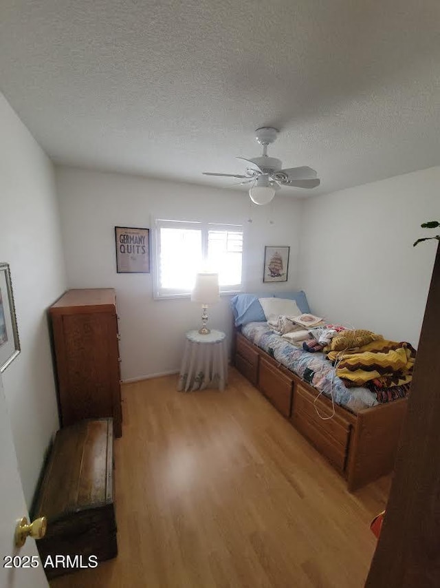 bedroom featuring a textured ceiling, ceiling fan, and light wood-type flooring