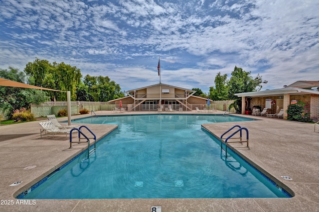 community pool featuring an outbuilding, a patio area, and fence