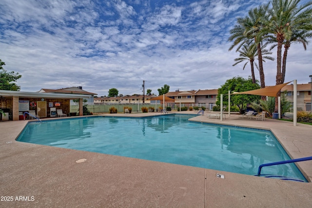 pool with a patio area and fence