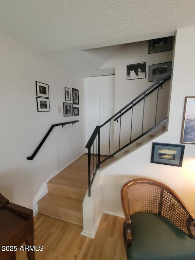 stairway featuring a textured ceiling and wood finished floors