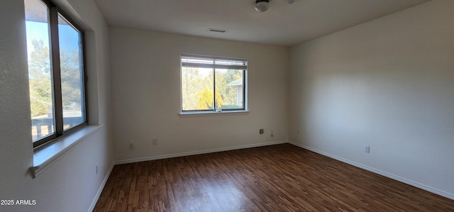 spare room with dark wood-type flooring and a wealth of natural light