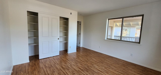 unfurnished bedroom with dark wood-type flooring and a closet