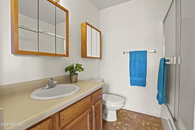 bathroom with parquet flooring, vanity, toilet, and an enclosed shower