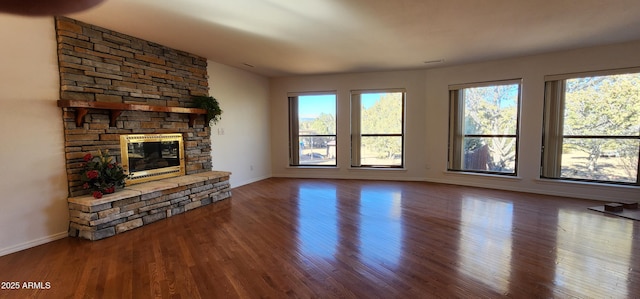 unfurnished living room featuring hardwood / wood-style flooring and a stone fireplace