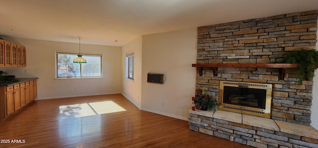 unfurnished living room with a stone fireplace and light wood-type flooring