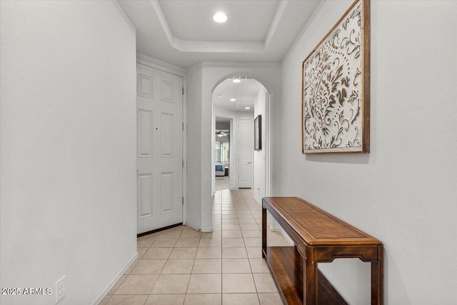 hallway with a raised ceiling and light tile patterned floors