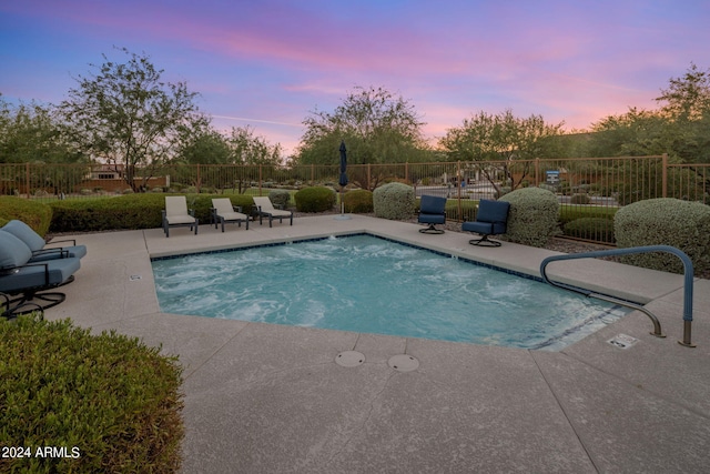 pool at dusk featuring a patio