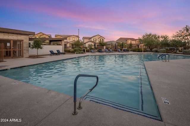 pool at dusk featuring a patio