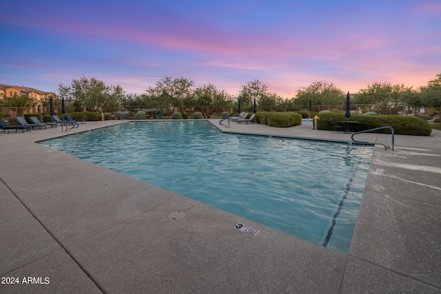 pool at dusk with a patio area