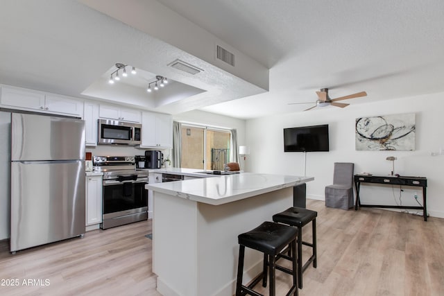 2021 E Osborn Rd Unit 9, Phoenix, AZ 85016 - kitchen with appliances with stainless steel finishes, a peninsula, white cabinets, and light wood-type flooring