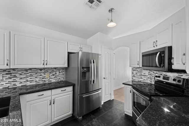 9631 E Palm Ridge Dr, Scottsdale, AZ 85260 - kitchen with stainless steel appliances, white cabinetry, backsplash, dark stone counters, and decorative light fixtures