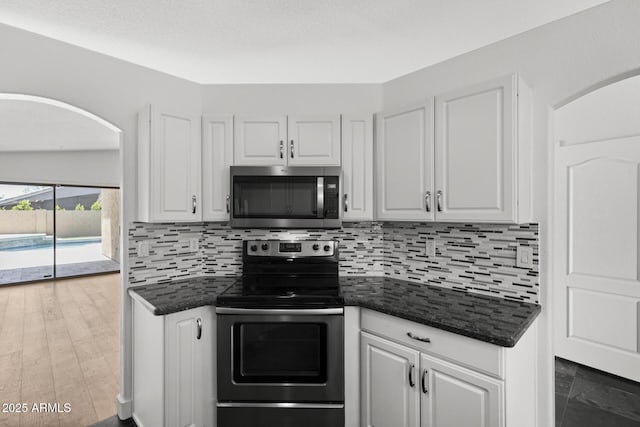 9631 E Palm Ridge Dr, Scottsdale, AZ 85260 - kitchen with stainless steel appliances, arched walkways, white cabinets, and backsplash