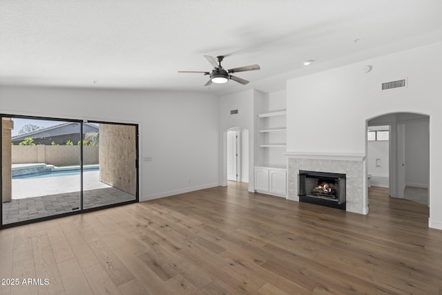 9631 E Palm Ridge Dr, Scottsdale, AZ 85260 - unfurnished living room with arched walkways, ceiling fan, built in shelves, baseboards, and wood finished floors