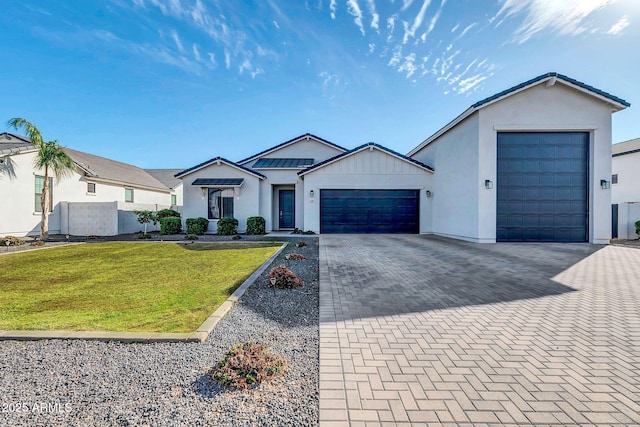 view of front of home with a garage, a front yard, decorative driveway, and stucco siding