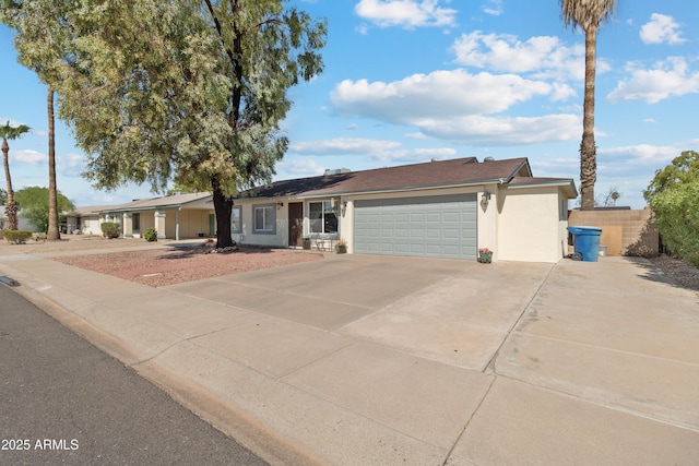 ranch-style home with an attached garage, fence, driveway, and stucco siding