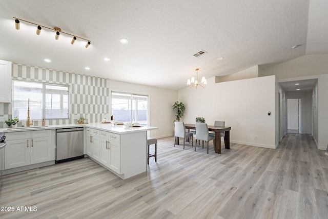 kitchen with white cabinetry, kitchen peninsula, decorative light fixtures, dishwasher, and sink