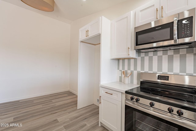 kitchen featuring appliances with stainless steel finishes, light hardwood / wood-style flooring, and white cabinetry