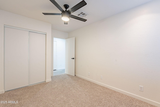 unfurnished bedroom with ceiling fan, light colored carpet, and a closet