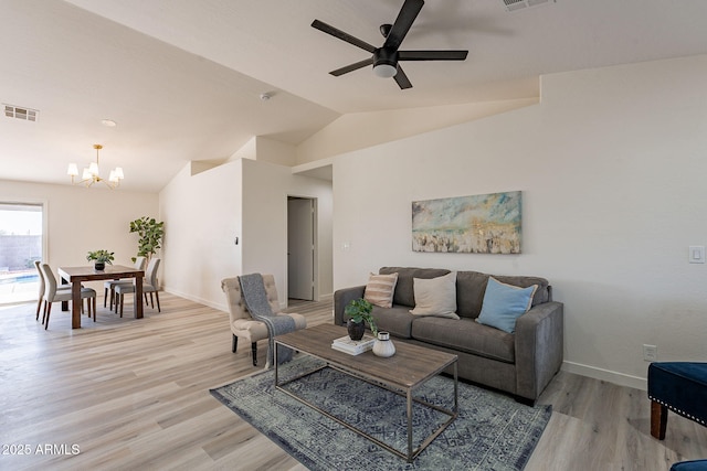 living room with ceiling fan with notable chandelier, vaulted ceiling, and light wood-type flooring