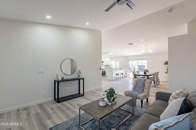 living room featuring light hardwood / wood-style floors and ceiling fan with notable chandelier