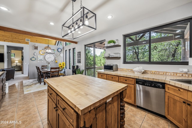 kitchen with butcher block counters, light tile patterned floors, dishwasher, a center island, and decorative light fixtures