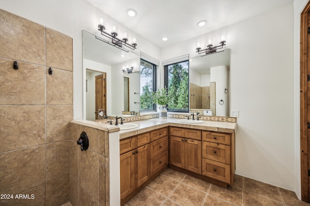 bathroom with tile patterned flooring, double sink vanity, and a tile shower