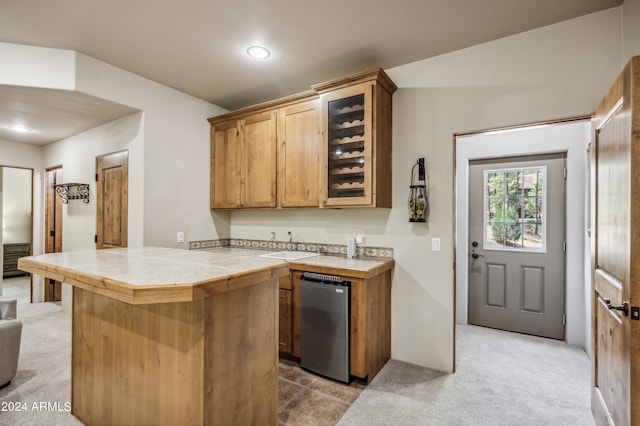 kitchen featuring kitchen peninsula, light colored carpet, tile countertops, and stainless steel dishwasher