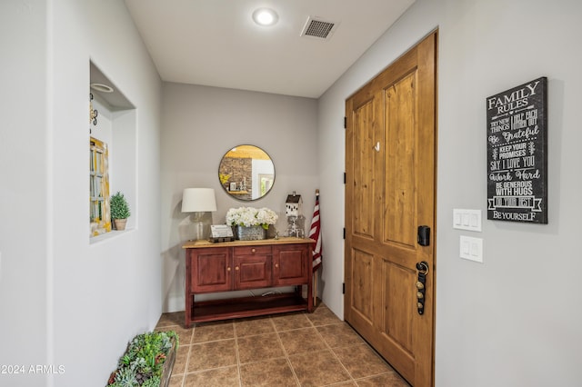 foyer entrance with dark tile patterned flooring and visible vents