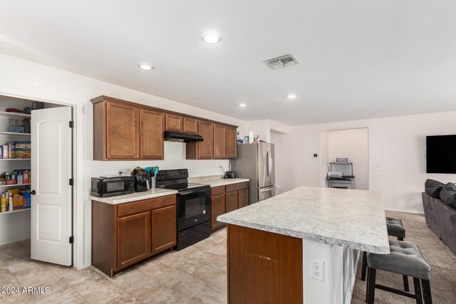 kitchen featuring black appliances, a center island, and a kitchen breakfast bar