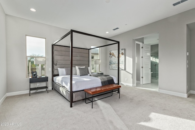 bedroom with light colored carpet and ensuite bath