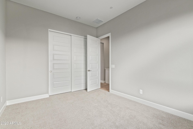 unfurnished bedroom featuring light colored carpet and a closet