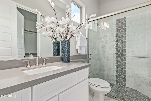 bathroom featuring a shower with shower door, toilet, and vanity