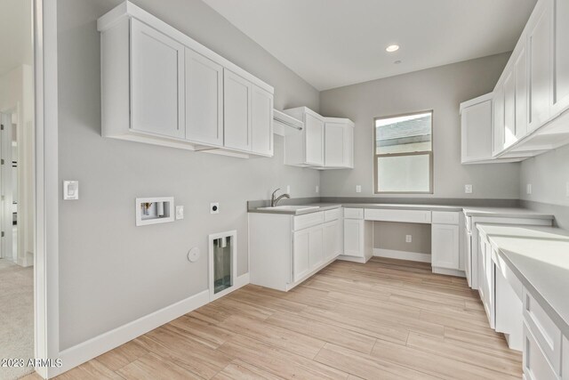 interior space with light wood-type flooring, white cabinetry, and sink