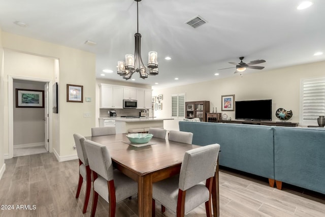 dining space featuring ceiling fan with notable chandelier and light wood-type flooring