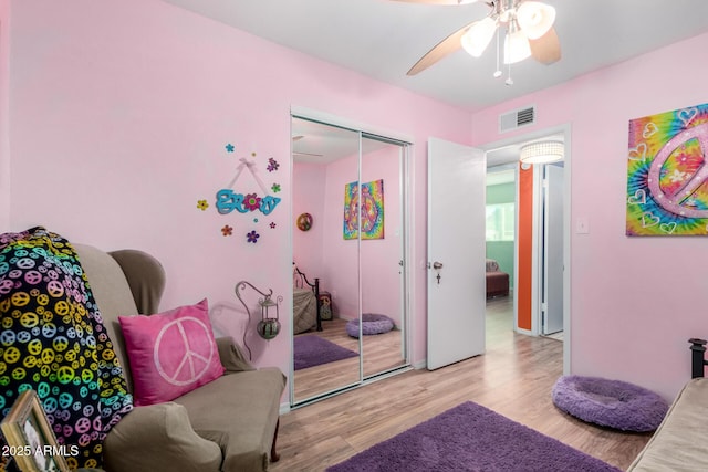 bedroom with ceiling fan, light hardwood / wood-style flooring, and a closet